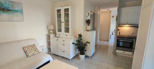 un salon avec un canapé et une cuisine dans l'établissement Garden studio 150 m from the beach, à Fréjus