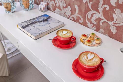 a table with two cups of coffee and cupcakes at B&B Cantiere dell'anima - Rooms of art in Trapani