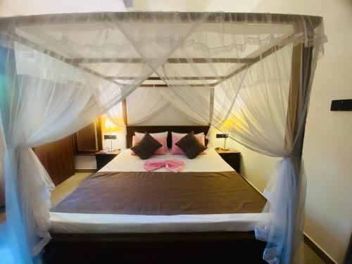 a bedroom with a canopy bed with a pink bow at Orana Villa in Ahangama