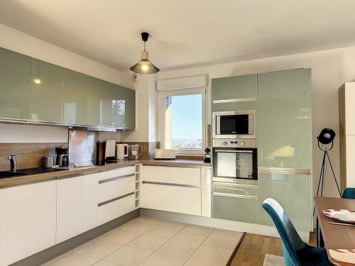 une cuisine avec des armoires blanches, une table et une fenêtre dans l'établissement Zenitude in Deauville, à Deauville