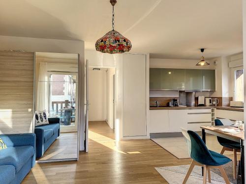 un salon avec un canapé bleu et une cuisine dans l'établissement Zenitude in Deauville, à Deauville