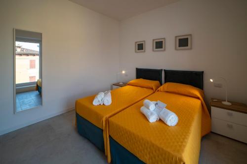 a bedroom with a orange bed with towels on it at Residence - LA ROSA DEI VENTI in Ghedi