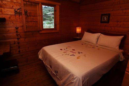 um quarto com uma cama num chalé de madeira em wooden Edge Of The Village em Ma'ale Gamla