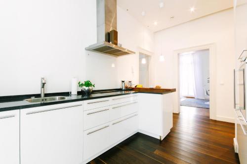 cocina con armarios blancos y suelo de madera en Deluxe Apartments LWP7, en Baden-Baden