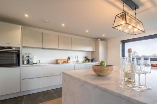 a kitchen with white cabinets and a counter with wine glasses at Mandalore 4 in Sotherton
