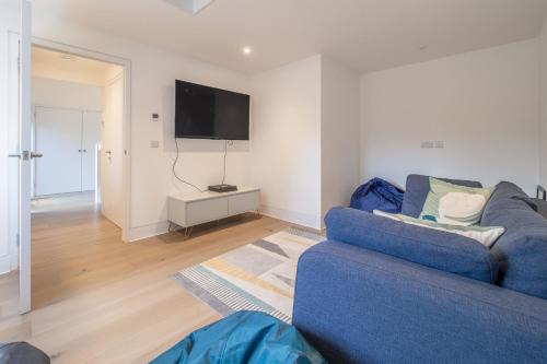 a living room with a blue couch and a flat screen tv at Mandalore 4 in Sotherton