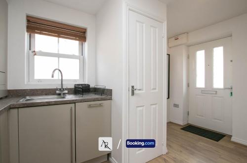 a kitchen with a sink and a window and a door at Cozy House By AR Properties Short Lets & Serviced Accommodation Colchester in Colchester