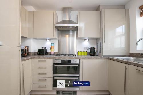 a kitchen with white cabinets and a stove top oven at Cozy House By AR Properties Short Lets & Serviced Accommodation Colchester in Colchester