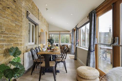 a dining room with a table and chairs and windows at Longborough House in Moreton in Marsh