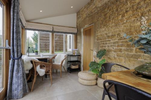 a dining room with a brick wall at Longborough House in Moreton in Marsh