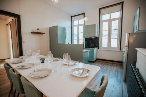 une cuisine avec une table avec des assiettes et des verres à vin dans l'établissement Grand appartement en centre ville, à Cambrai