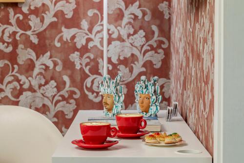 a table with two red cups and plates of food at B&B Cantiere dell'anima - Rooms of art in Trapani