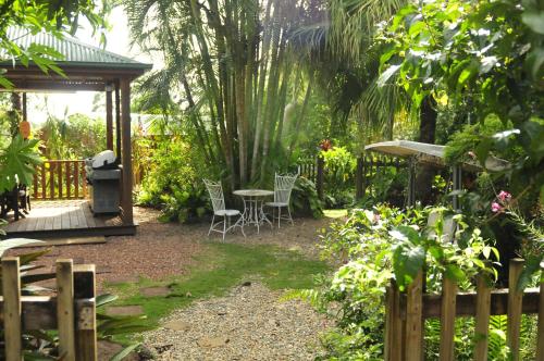 a garden with a table and chairs and a gazebo at Kookaburra Motel Yungaburra in Yungaburra