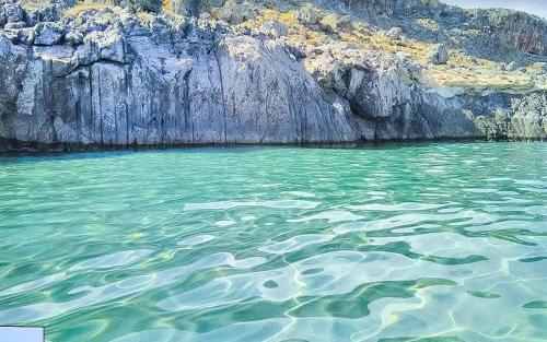a large body of water next to a rocky cliff at Aggel's Infinity View Villa - private pool in Káto Episkopí