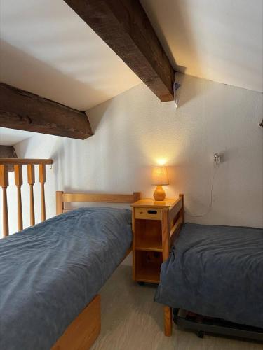 une chambre avec deux lits et une table avec une lampe dans l'établissement SP520-M344 Appartement 2 pièces SAINT PIERRE LA MER, à Saint Pierre La Mer