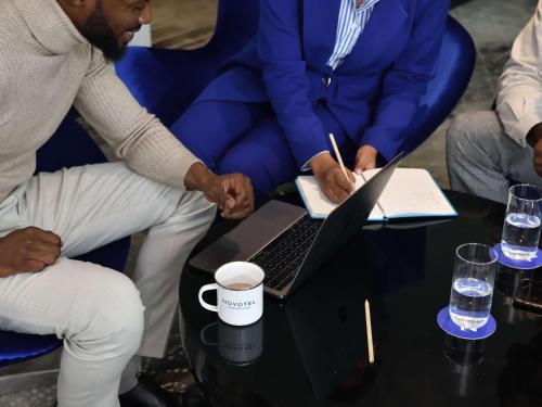 a group of people sitting around a table with a laptop at Novotel Nairobi Westlands in Nairobi