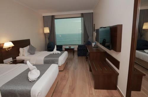 a hotel room with two beds and a flat screen tv at The Quilon Beach Hotel and Convention Center in Kollam