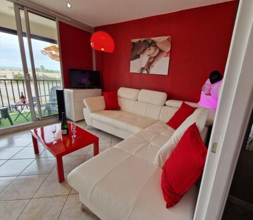 - un salon avec un canapé blanc et des murs rouges dans l'établissement Naturiste Cap d'Agde Héliopolis F 61, au Cap d'Agde