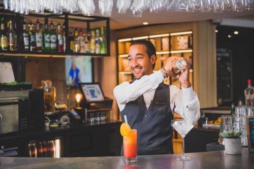 a man standing at a bar pouring a drink at Campanile PRIME - Nice Airport in Nice
