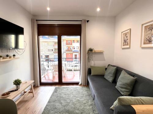 a living room with a couch and a balcony at Apartaments Casa Mata - L'Amfitriona in Esterri d'Àneu