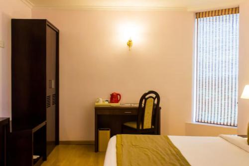 a bedroom with a desk and a bed and a chair at The Quilon Beach Hotel and Convention Center in Kollam
