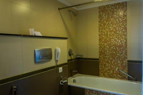 a bathroom with a tub and a phone on the wall at The Quilon Beach Hotel and Convention Center in Kollam