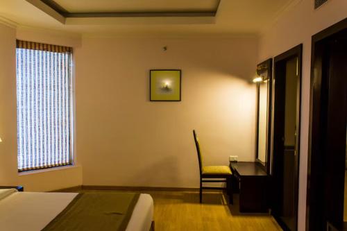 a hotel room with a bed and a desk and a window at The Quilon Beach Hotel and Convention Center in Kollam
