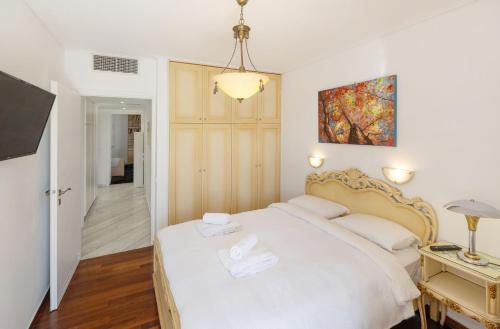 a bedroom with a white bed and a tv at Nice Sea View Elegant Apartment in Athens
