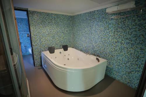 a bath tub in a bathroom with blue tiles at The Quilon Beach Hotel and Convention Center in Kollam