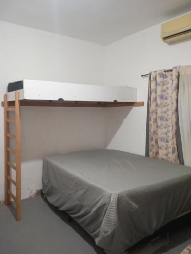 a bed in a room with a shelf on the wall at Apto Casa A Simples, Central e Aconchegante in Corumbá
