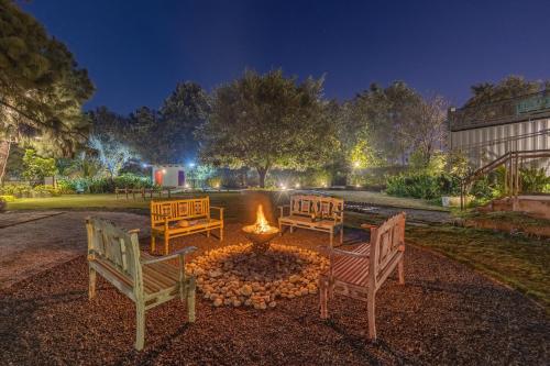 a group of chairs around a fire pit at night at ELIVAAS Hidden Oasis 4BHK with Pool, Mud House & Container House in Dhauj