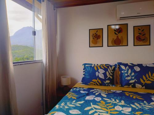 a bedroom with a bed and a window with a view at Hospedagem Encantos da Serra in Itatiaia