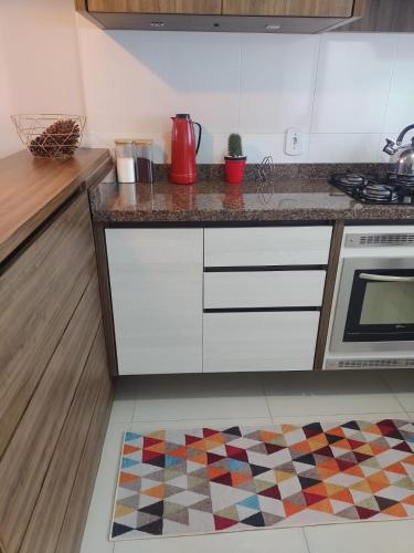 a kitchen with white cabinets and a kitchen rug at B&B Apartamento acolhedor Bem localizado, Próximo ao aeroporto in São José dos Pinhais