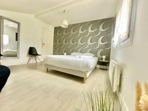 une chambre avec un lit blanc et un mur dans l'établissement Le Refuge du Palais, à Le Palais-sur-Vienne