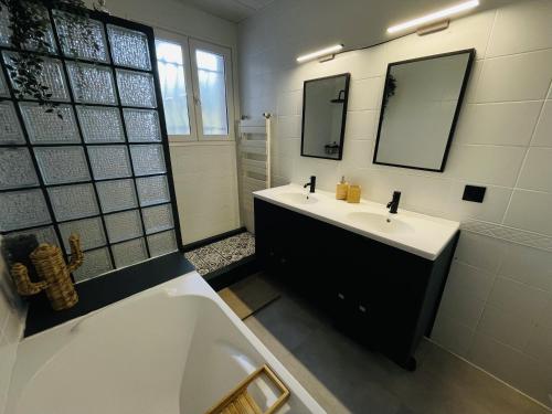 ein Badezimmer mit einer weißen Badewanne, einem Waschbecken und einer Badewanne in der Unterkunft Villa Casalera - piscine, spacieuse & familiale in Dax