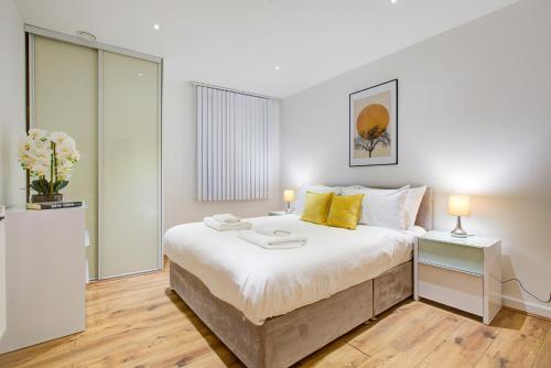 a bedroom with a large white bed with yellow pillows at Hybrid Resi - London, Greenwich near O2 Arena in London