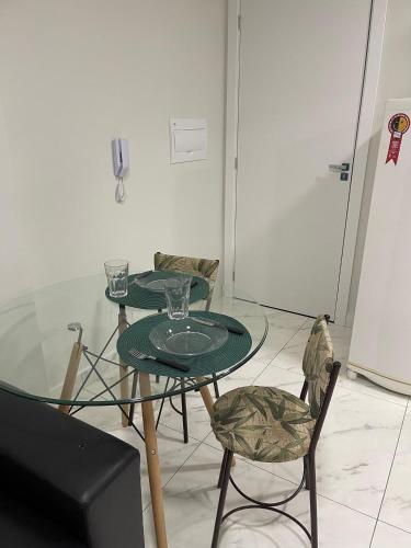 a glass table with two chairs and a table with glasses on it at Imóvel climatizado, localizado em um prédio novo e equipado com tudo o que você precisa para uma experiência de hospedagem incrível na cidade de Toledo. in Toledo