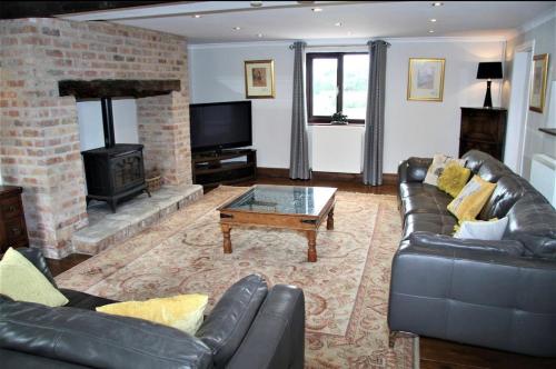 a living room with a leather couch and a fireplace at Stonetrough Cottage in Stoke on Trent