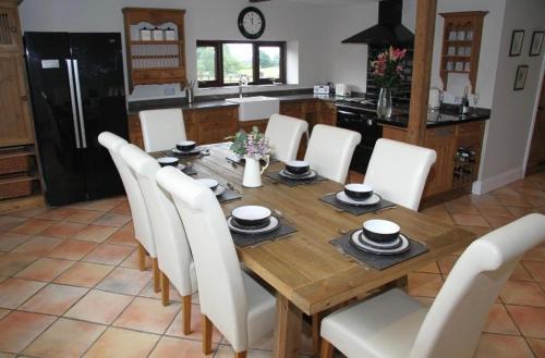 a wooden table with white chairs and a kitchen at Stonetrough Cottage in Stoke on Trent