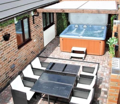 a patio with a table and chairs and a hot tub at Stonetrough Cottage in Stoke on Trent