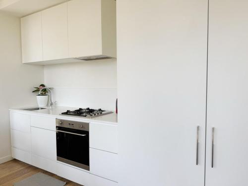 a white kitchen with white cabinets and a stove at FutureStay AI in Melbourne