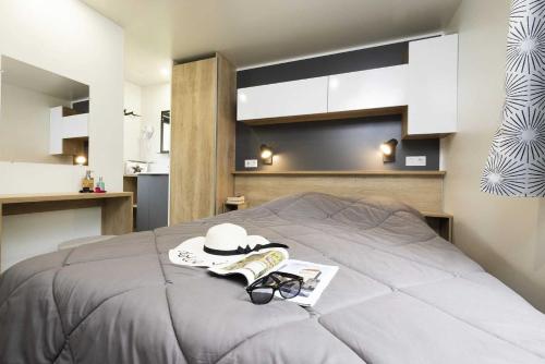 una camera da letto con un letto con cappello e occhiali di Camping 4 étoiles - Piscine - eeihec a Loupiac
