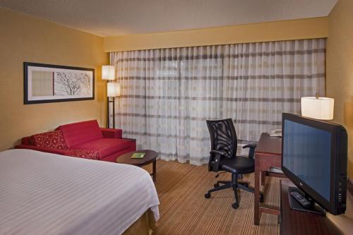 a hotel room with a bed a desk and a tv at Courtyard by Marriott Richmond Northwest in Henrico