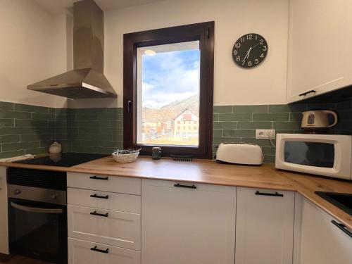 a kitchen with a window and a clock on the wall at Apartaments Casa Mata - L'Amfitriona in Esterri d'Àneu
