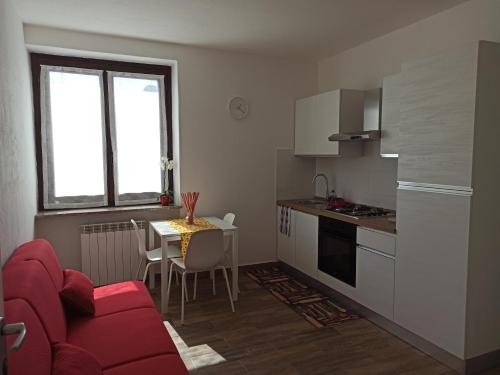 a small kitchen with a red couch and a table at B&B FIOR DI CAMPO in Ronago