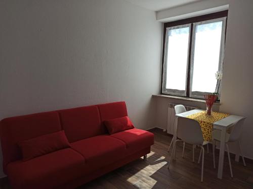 a living room with a red couch and a table at B&B FIOR DI CAMPO in Ronago