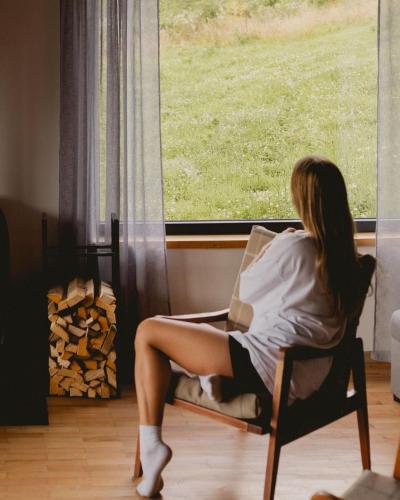 a woman sitting in a chair looking out a window at Гірські будиночки in Zhdenievo