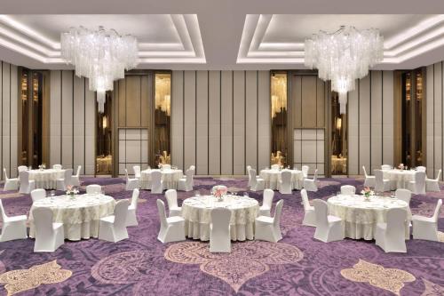 a ballroom with white tables and chairs and chandeliers at Courtyard by Marriott Siliguri in Siliguri