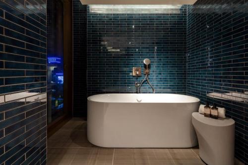 a bath tub in a bathroom with blue tiles at The Londoner in London