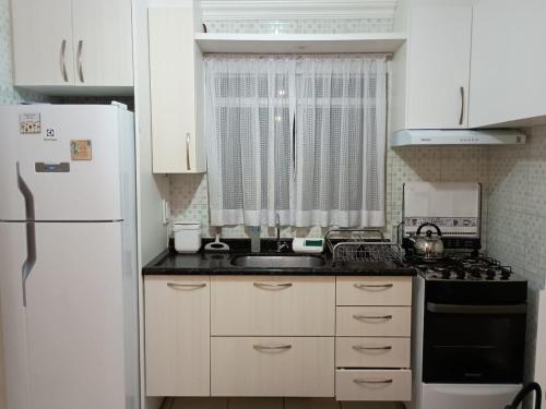 a kitchen with white cabinets and a white refrigerator at B&B Apartamento a 10 minutos do Aeroporto in São José dos Pinhais